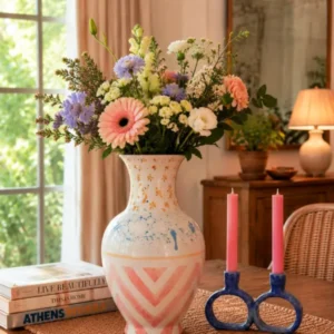 Handmade hand-painted ceramic vase with pink geometric patterns and floral arrangement on wooden table